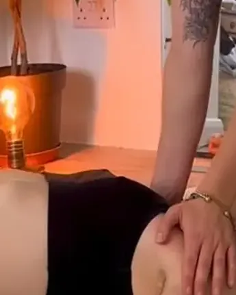 A therapist’s hand on a client’s shoulder during a floor massage at home